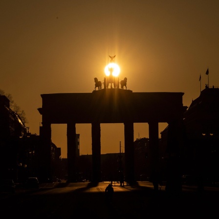 Die Sonne geht hinter dem Brandenburger Tor auf.