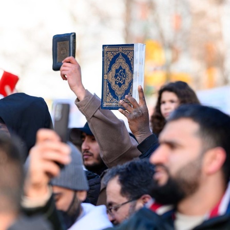 Demonstrationsteilnehmer halten den Koran in die Höhe.