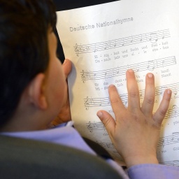 Festliche Einbürgerung im Rathaus Neukölln. Junge übt deutsche Nationalhymne. © IMAGO/ Bernd Friedel