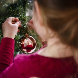 Ein Mädchen schmückt den Weihnachtsbaum