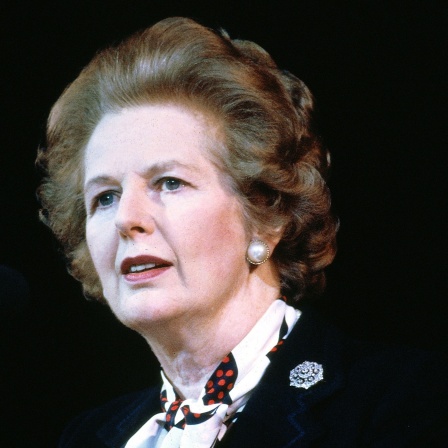 Margaret Thatcher im Porträt - sie schaut mit perfekt frisierten Haaren ernst zur Seite, der Hintergrund ist schwarz, Aufnahme von 1980