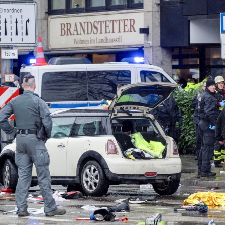 13.02.2025, Bayern, München: Polizisten untersuchen ein Auto in der Nähe des Einsatzortes. In der Münchner Innenstadt ist ein Fahrzeug in eine Menschengruppe gefahren. 