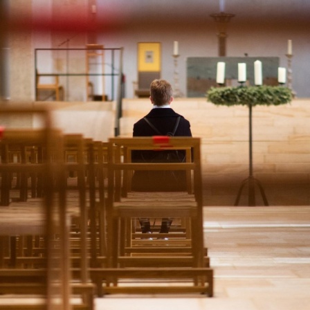 Eine Frau sitzt alleine im Hildesheimer Dom. 
