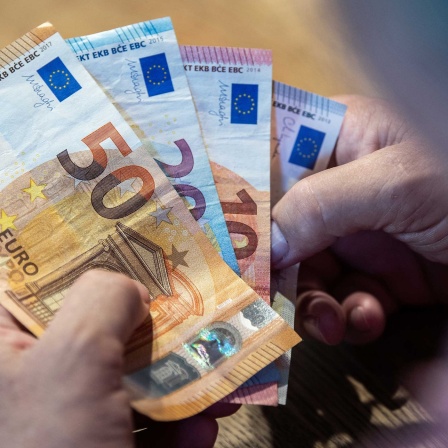Symbolbild: Ein Mensch hält Euro-Scheine in der Hand