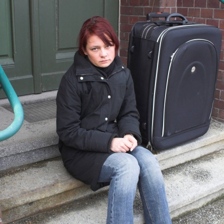 Junge Frau sitzt allein mit Koffer auf einer Treppe: Mit 18 Jahren erwachsen - für Pflege- und Heimkinder endet dann in der Regel die Jugendhilfe. Die jungen Menschen stehen plötzlich alleine da und werden zu Niemandskindern: Niemand fühlt sich für sie verantwortlich - auch die Behörden nicht.