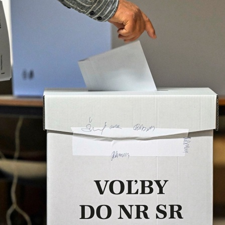Ein Mann steckt bei den vorgezogenen Parlamentswahlen in der Slowakai seinen Stimmzettel in eine Wahlurne.