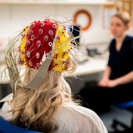 Eine Probandin trägt eine EEG-Haube mit Elektroden für die EEG-Messung (Bild: picture alliance/dpa/Jacob Schröter)