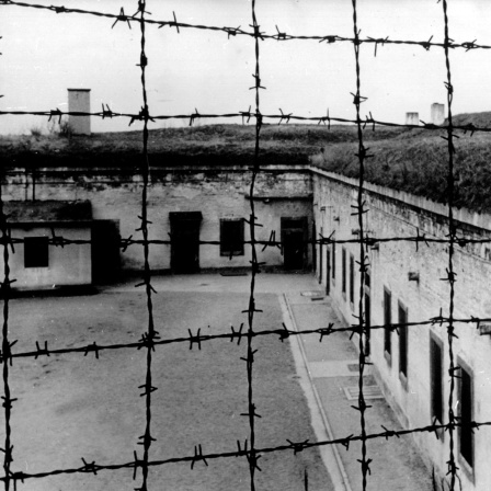 Blick durch Stacheldraht auf die Gebäude des 1941 von der SS errichteten Konzentrationslagers im tschechischen Theresienstadt. 