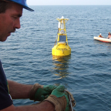 Ein Techniker arbeitet 2005 an Bord des deutschen Forschugsschiffs &#034;Sonne&#034;, im Hintergrund zu sehen eine Boje, die Teil eines von GITEWS entwickelten Tsunami-Warnsystems sein wird. Das von deutschen und indonesischen Forschern entwickelte System umfasst Sensoren am Meeresboden und Bojen auf der Meeresoberfläche, die Erdbeben- und Tsunami-Aktivitäten messen sollen.