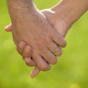 Männerhand mit Ehering hält eine Frauenhand