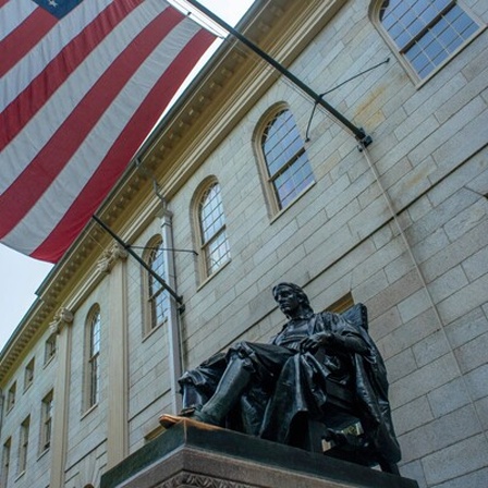 Die Statue von John Harvard (Daniel Chester French) steht auf dem Campus der Harvard-Universität. Über der Statue weht die US-Flagge.