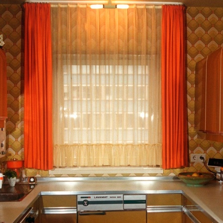 Ein Fenster mit orangenen Vorhängen in einer Küche aus den siebziger Jahren.