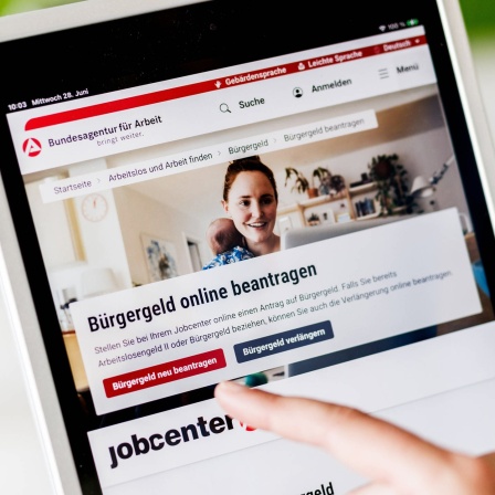 Eine Frau tippt auf einem Tablet auf einen Link zum Beantragen des Bürgergeldes