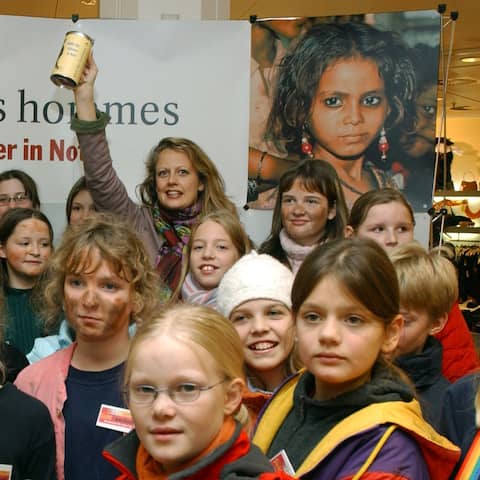 Die TV-Moderatorin Barbara Schöneberger hält bei einer vom Kinderhilfswerk "terre des hommes" inmitten von Kindern einen Sammelbecher hoch.