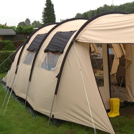 Ein großes beiges Zelt auf einem Campingplatz.