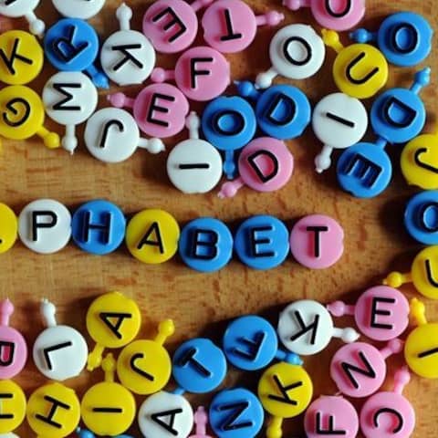 Das Wort Analphabet liegt aus einzelnen Buchstaben des Familienspiels &#034;Buchstabensuppe&#034; mit vielen anderen bunten Buchstaben auf einem Tisch