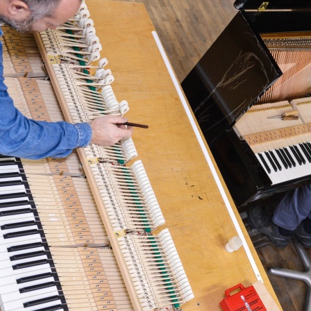 Klavierbauer Alexander Reul (l) und der Auszubildende David Will bei der Endregulierung von Flügel- und Pianomechaniken