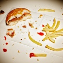Ein angebissener Burger und Reste von Pommes liegen auf einem Tisch.