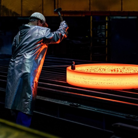 Ein Mitarbeiter stempelt im ThyssenKrupp Werk Rothe Erde einen glühenden Rohling.