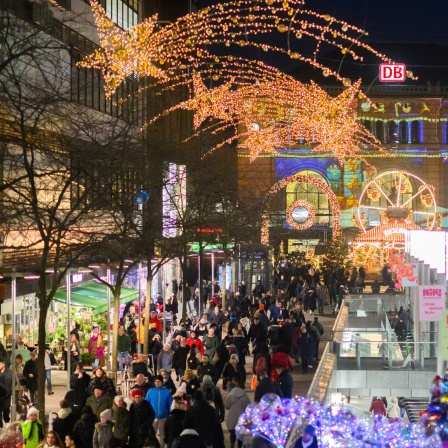 Passanten laufen durch die weihnachtlich geschmückte Innenstadt vor dem Hauptbahnhof in Hannover