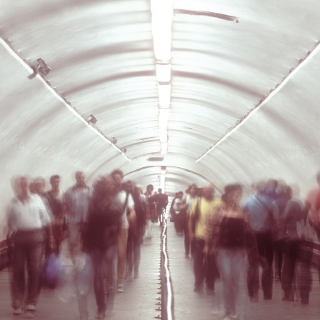 Menschen laufen durch einen Tunnel und auf dem Fot liegt ein Effekt, dass alles verschwommen wirken lässt.