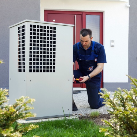 Ein Heizungsmonteur montiert das Gehäuse für eine Wärmepumpe im Rahmen einer Heizungsmodernisierung