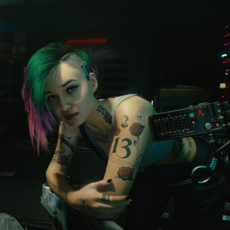 Screenshot aus dem Rollenspiel "Cyberpunk 2077:Eine junge Frau mit vielen Tattoos und bunten, auf einer Seite abrasierten Haaren beugt sich zum Betrachter und blickt ihn ernst an. Hinter ihr befindet sich der Neon-Schriftzug "Lizzie's Bar" 