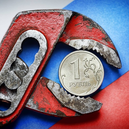 Ein-Rubel-Münze vor russischer Fahne in der Zange