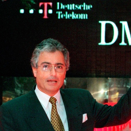 Der damalige Vorstandsvorsitzende der Deutschen Telekom, Ron Sommer, zeigt vor der Deutschen Börse in Frankfurt am Main auf die Anzeigentafel auf der der Erstausgabepreis von 28,50 DM für die Telekom-Aktie zu lesen ist (Archivfoto vom 17.11.1996).