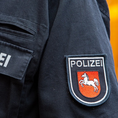 Der Schriftzug "Polizei" und das Niedersachsen-Pferd auf einer Polizeiuniform.