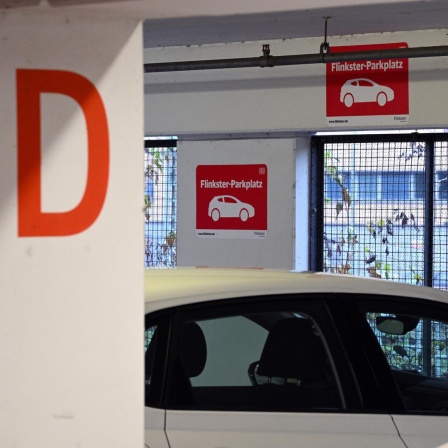 Schilder mit dem roten Logo für "Flinkster-Parkplatz" ist in dem Parkhaus am Hauptbahnhof vor einer Parkbucht angebracht.