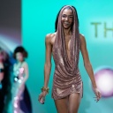 Ein weibliches Model läuft bei der Fashion Week in New York lächelnd über einen Laufsteg.