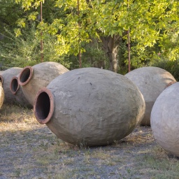 In einem Garten liegen mehrere große Tongefäße, sogenannte Quevris, die in Georgien zur traditionellen Weinherstellung verwendet werden.