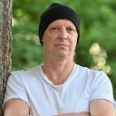 Dramatiker und Regisseur Armin Petras, er lehnt mit verschränkten Armen an einem Baum.