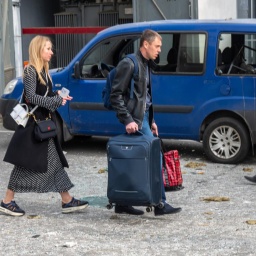Ein Mann und eine Frau mit Gepäck verlassen die Stadt Charkiw.