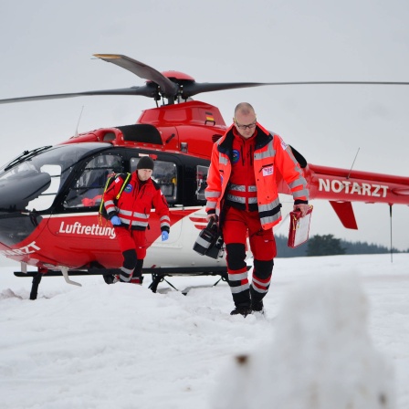 Ein Notarzt und ein Rettungsassistent der Luftrettung DRF sind mit einem Helikopter unterwegs zu einer verunglückten Person