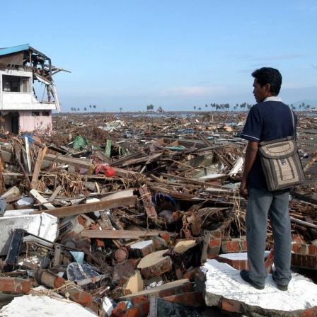 Ein Mann steht zwischen den Trümmern seines Hauses und Heimatortes in Banda Aceh nach dem Tsunami von 2004