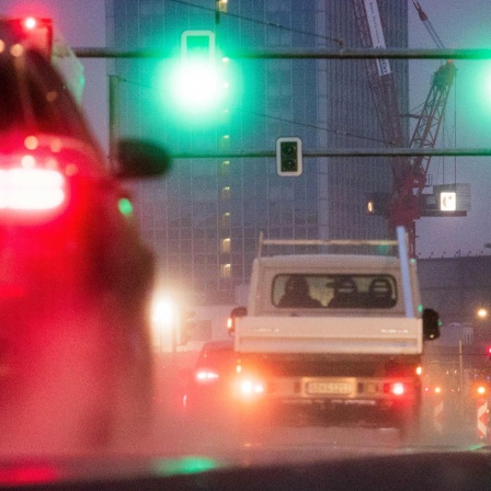 Autos und ein Motorrad fahren an eine Ampelkreuzung am Alexanderplatz.