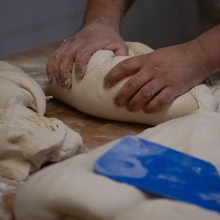 Ein Bäcker knetet Teig in der Backstube von "Der Göttinger Feuerbäcker". Die Kostensteigerungen für Energie, Treibstoffe und Mehl bringen das Bäckerei-Handwerk zunehmend in Schwierigkeiten.