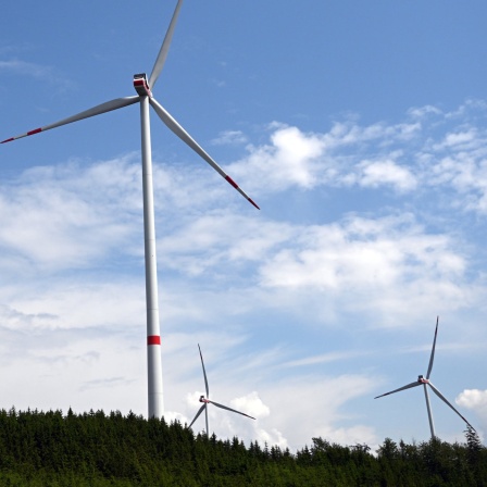 ARCHIV - 06.06.2023, Nordrhein-Westfalen, Bad Berleburg: Wolken ziehen über Windräder zur Stromerzeugung. In Nordrhein-Westfalen wird es für sechs Monate ein Genehmigungsmoratorium für Windkraftanlagen außerhalb bestimmter Planungszonen geben.