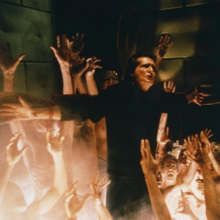 Szene aus dem Film "Der Exorzist III": Hände griefen nah einem cMann am Kreuz