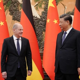Der chinesische Präsident Xi Jinping (re.) mit Bundeskanzler Olaf Scholz (SPD). Im Hintergrund sind deutsche und chinesische Fahnen zu sehen. 