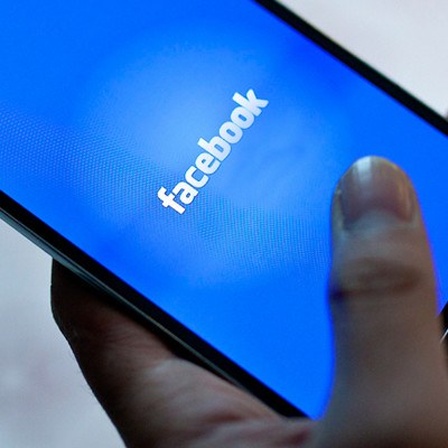 Eine Hand surft auf einem Smartphone-Screen bei Facebook
