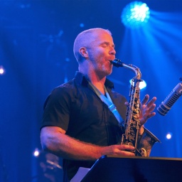 Ein Mann steht auf einer Bühne und spielt Alt-Saxofon.