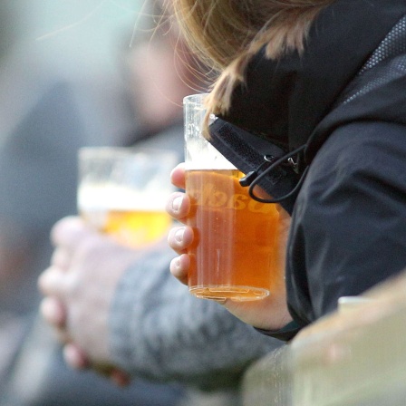 Zwei Zuschauer halten Plastikbecher mit Bier in der Hand.