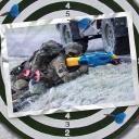 Eine Bildmontage zeigt eine Dartscheibe. Darauf ist eine Postkarte zu sehen. Sie zeigt einen Bundeswehrsoldaten, der anstelle eines Gewehrs mit einer großen Wasserpistole zielt. Im Gurthalfter steckt eine rosa Spielzeug-Pistole