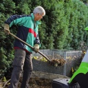 Mann steht an einem Komposthaufen und befüllt ihn mit Laub