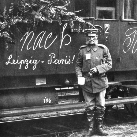 Soldat im Ersten Weltkrieg vor einem Zug mit der Aufschrift &#034;Nach Paris - Leipzig / Paris!&#034;