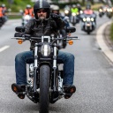 Auf dem Foto fahren zahlreiche Harley Davidson-Fahrer auf den Fotografen zu. Im Vordergrund ist ein Fahrer mit einem gezwirbelten grauen Backenbart im Gesicht.