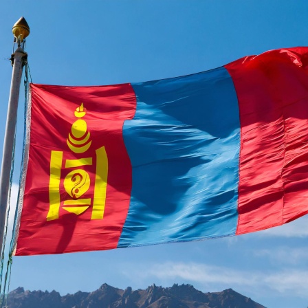 Die Nationalflagge der Mongolei vor blauem Himmel